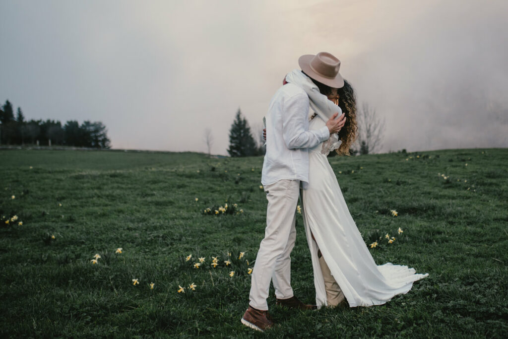 Jeunes mariés après la prononciation de leurs vœux dans une prairie au cœur des Pyrénées dans les nuages. Elopement.