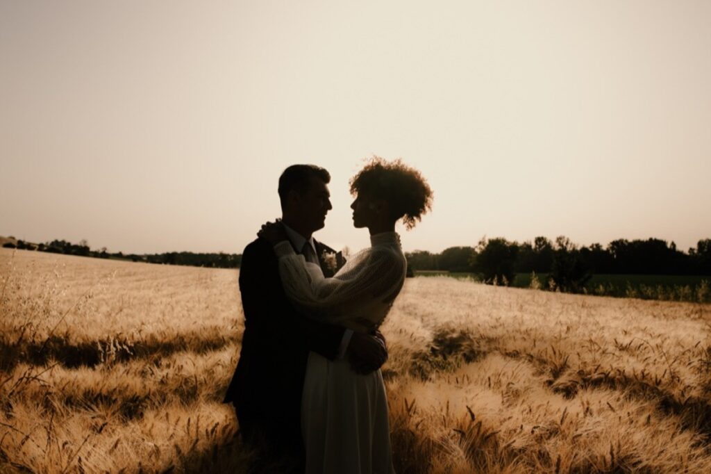 Reportage mariage. Moment de la séance couple dans un champ de blé sous le soleil couchant