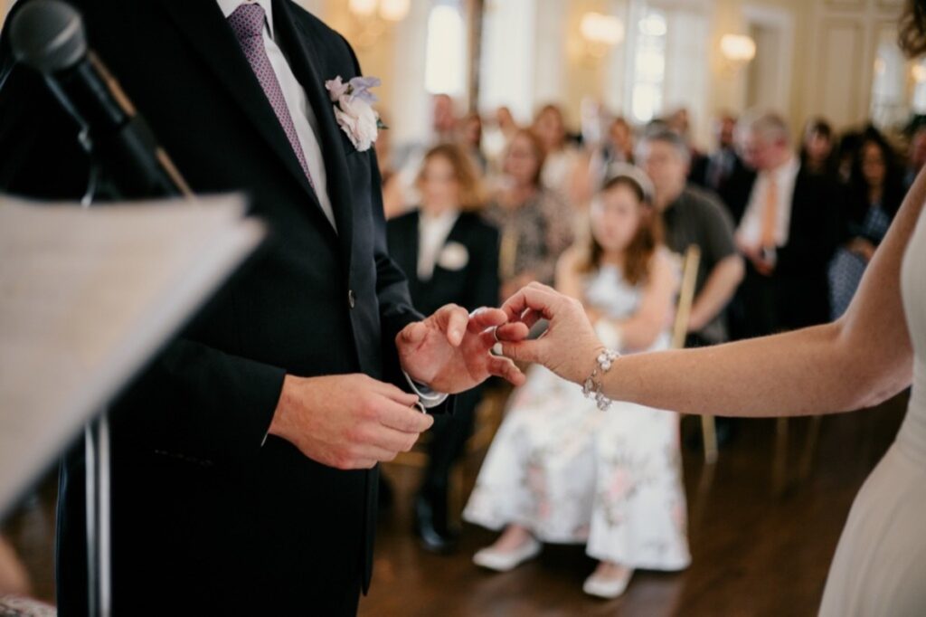 Documentaire/reportage mariage en pleine cérémonie d'échange des alliances. Photos sur la main de la mariée qui met l'alliance à son futur mari.