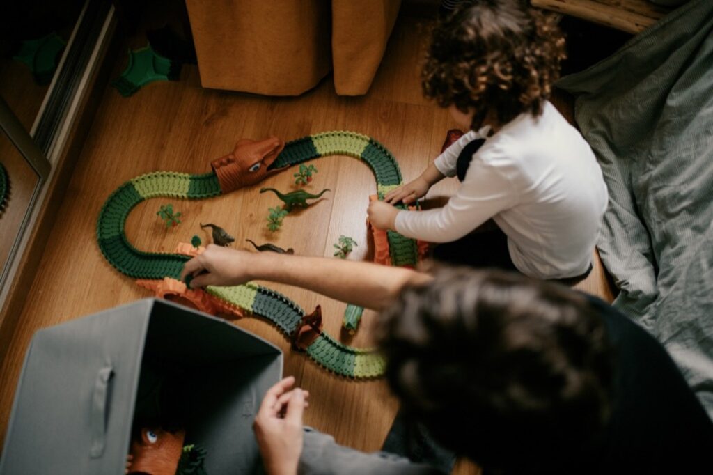 Séance famille à la maison. jeu dans la chambre du grand frère. Le grand frère installe un circuit auto dans sa chambre