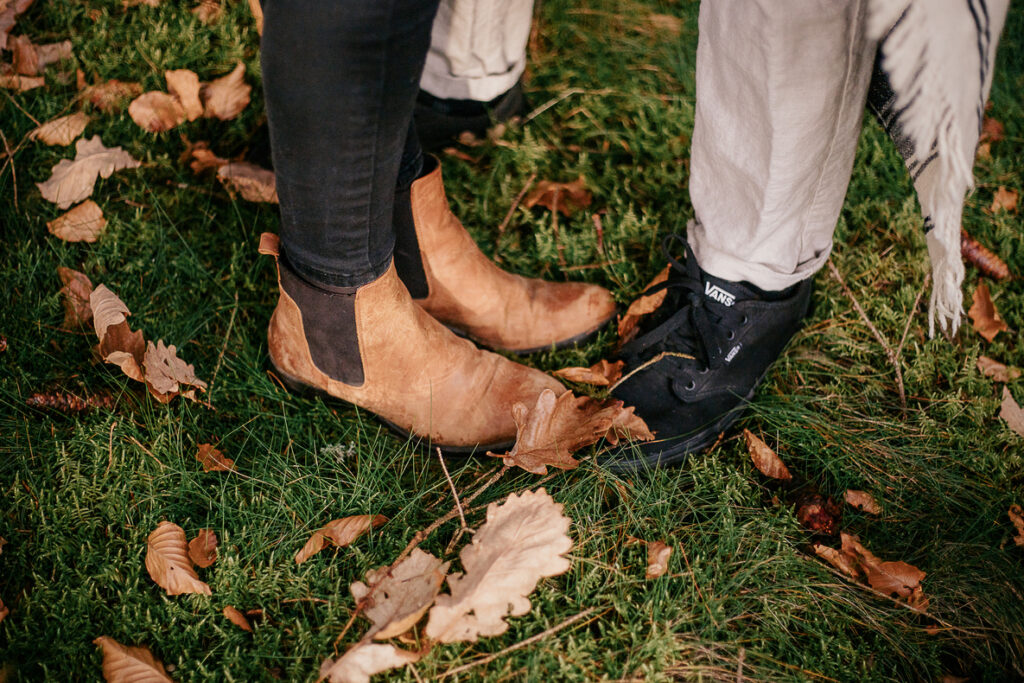 photo prise par @sophiebacherephotos. Séance couple au coeur de la montagne noire dans l'Aude. La photo montre un plan des chaussures du couple dans la mousse décorée de feuille morte des arbres au-dessus.