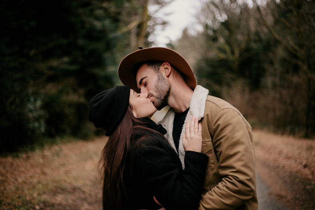 Photo prise par @sophiebacherephotos. Séance couple au coeur de la montagne noire dans l'Aude. La photo montre le couple entouré de forêt sur une route s'embrassant.