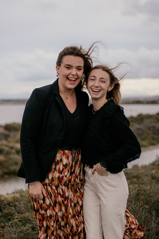 photo prise par @sophiebacherephotos. Séance portrait aux salins de Gruissan Aude. La photo montre la jeune fille venue avec son amie, elles sont debout sur les bords des salins, leurs cheveux flottent dans le vent.