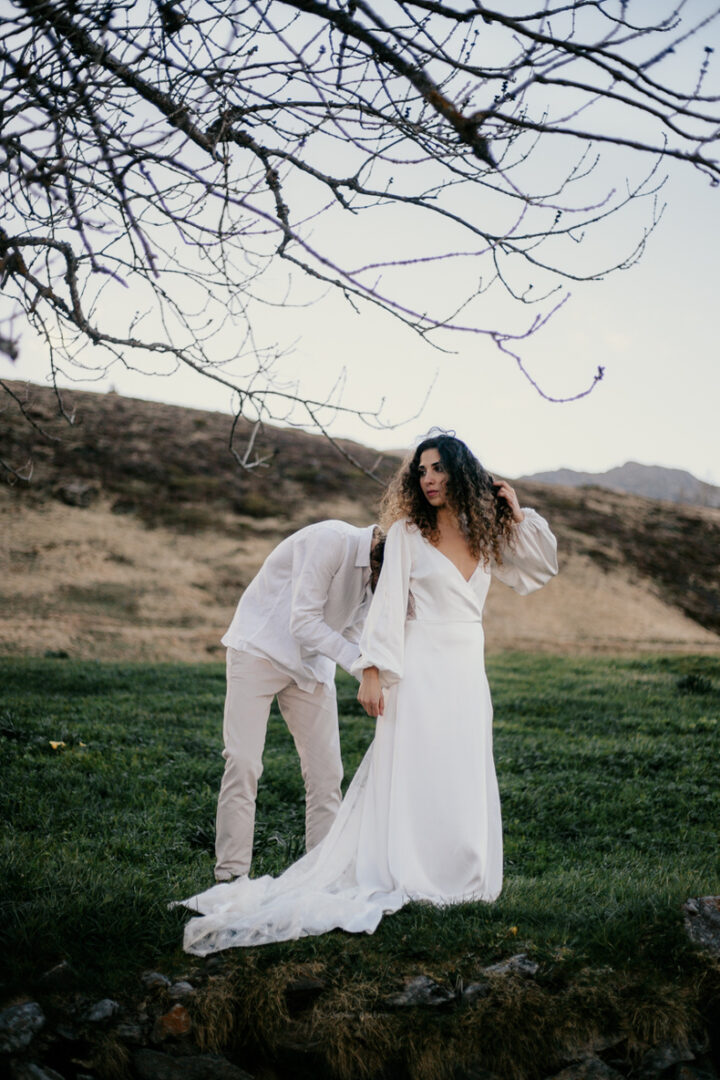 Photo prise par @sophiebacherephotos, le marié boutonne la robe de la mariée