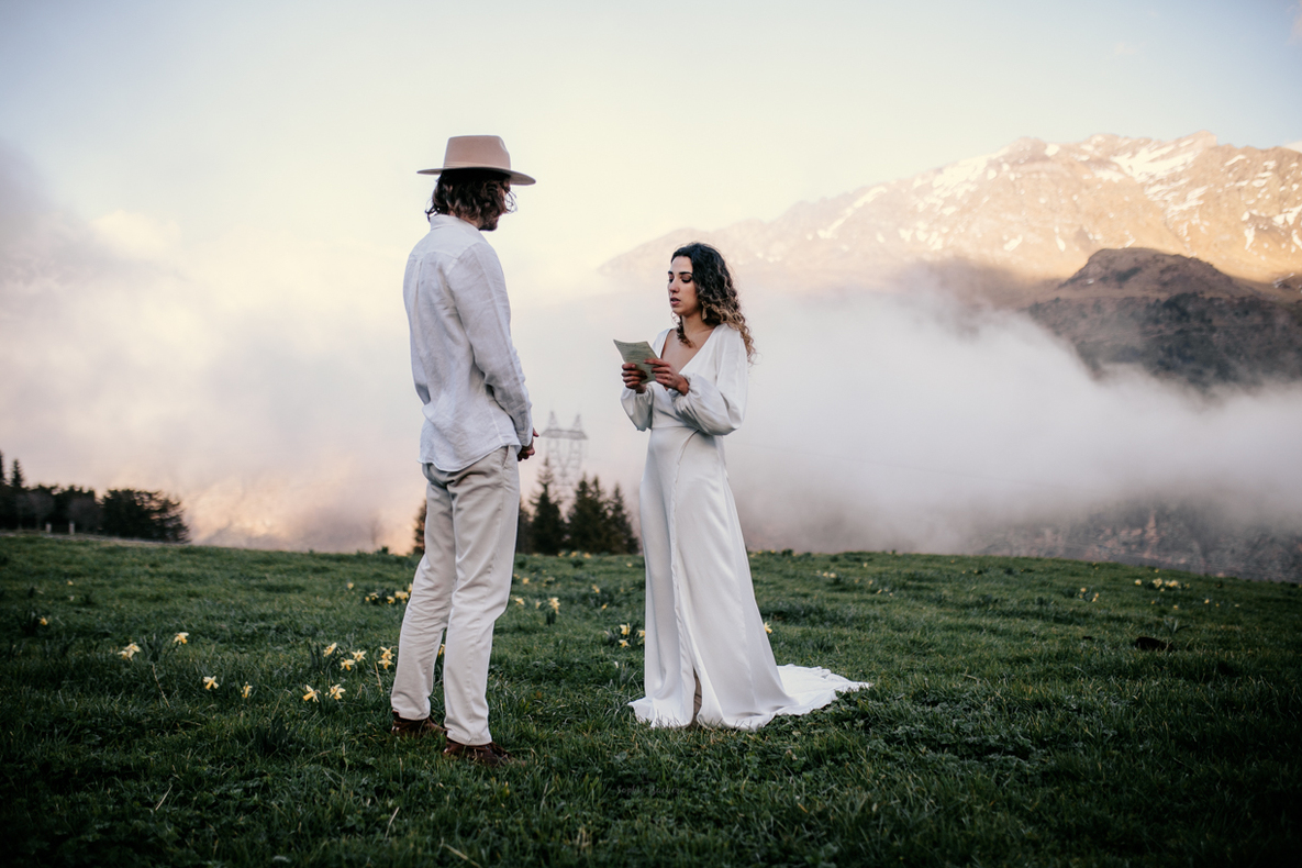 Photo prise par @sophiebacherephotos, plan des mariés qui s'embrasse en arrière plan nuages sur la montagne.