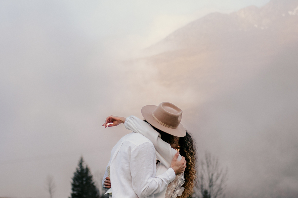 Photo prise par @sophiebacherephotos, plan des mariés qui s'embrasse en arrière plan nuages sur la montagne.