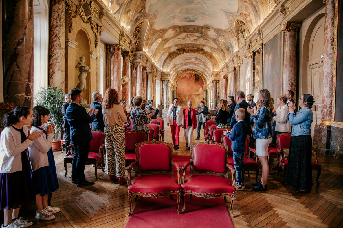 Photo prise par @sophiebacherephotos. La photo montre le couple de futures mariées s'engageant dans l'allée direction du maire