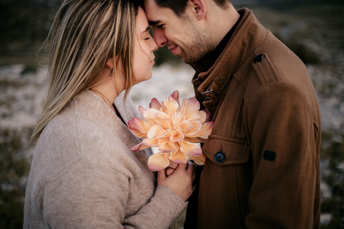 Séance couple par @sophiebacherephotos. La séance photo de couple sur les hauteurs de la clappe près de Narbonne Plage. La photo montre le couple front contre front, tenant une fleur entre eux deux. 