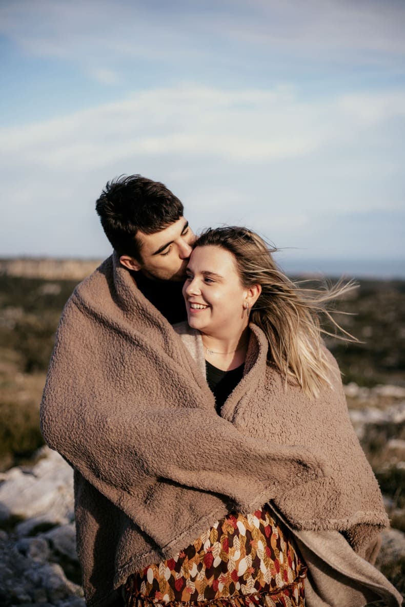 Photo prise par @sophiebacherephotos. Séance couple sur les hauteurs de la Clape à Narbonne Plage dans l'Aude en Occitanie. La photo montre le couple s'enlaçant dans une couverture