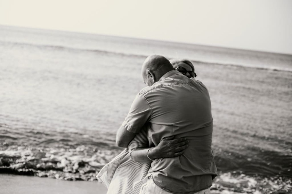 Photo prise par @sophiebacherephotos. La photo montre un couple dansant dans les vagues de la mer. photo en noir et blanc