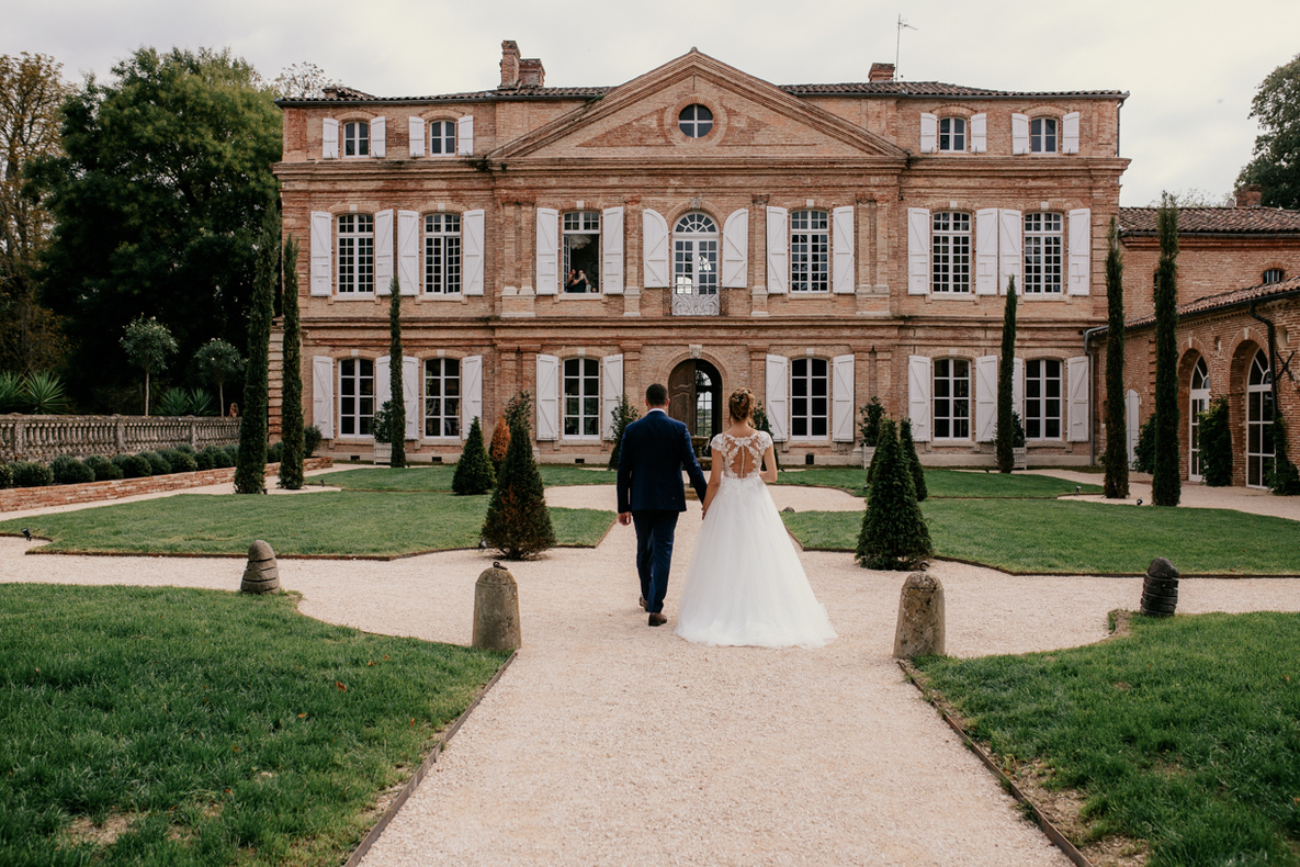 Mariage au Château du PUJOLET 31 Photo prise par @sophiebacherephotos au Château du Pujolet dans le 31, photo montrant les mariés marchant en direction du château
